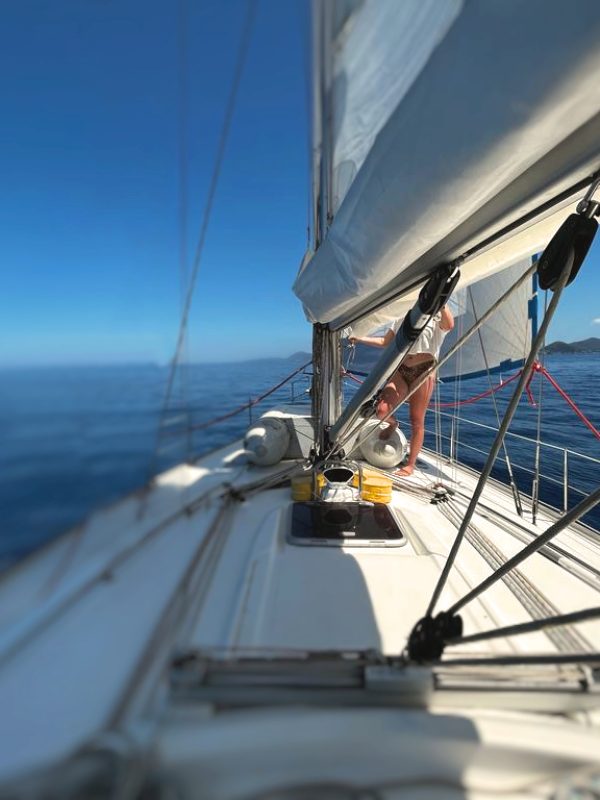 weißes Segelschiff auf blauem Meer mit Frau in Bikini am Mast